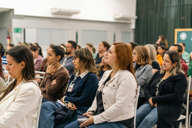 A diverse group of adults attentively listens during an indoor educational session.