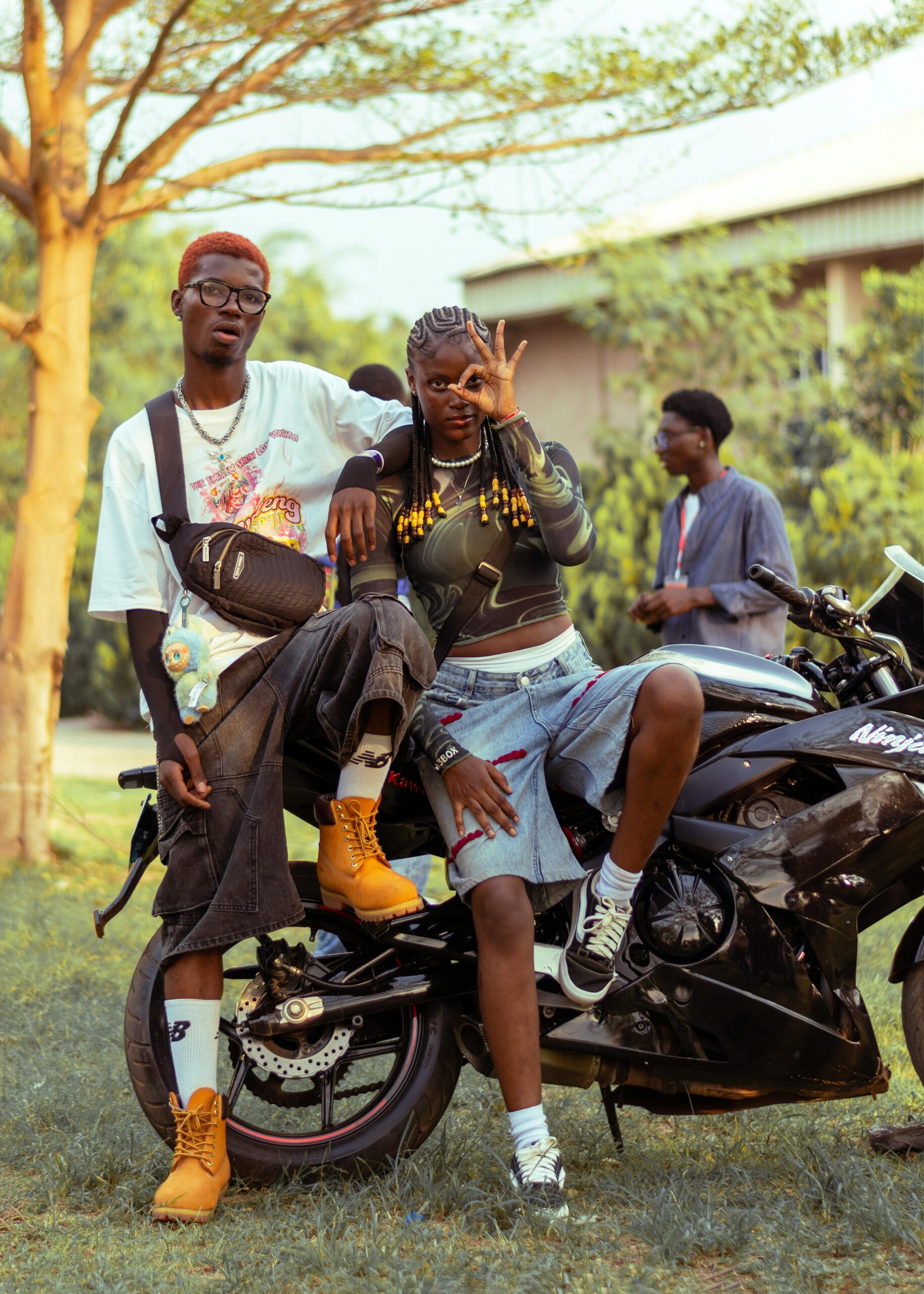 Young adults posing with motorcycle in vibrant fashion outdoors, Ado Ekiti, Nigeria.