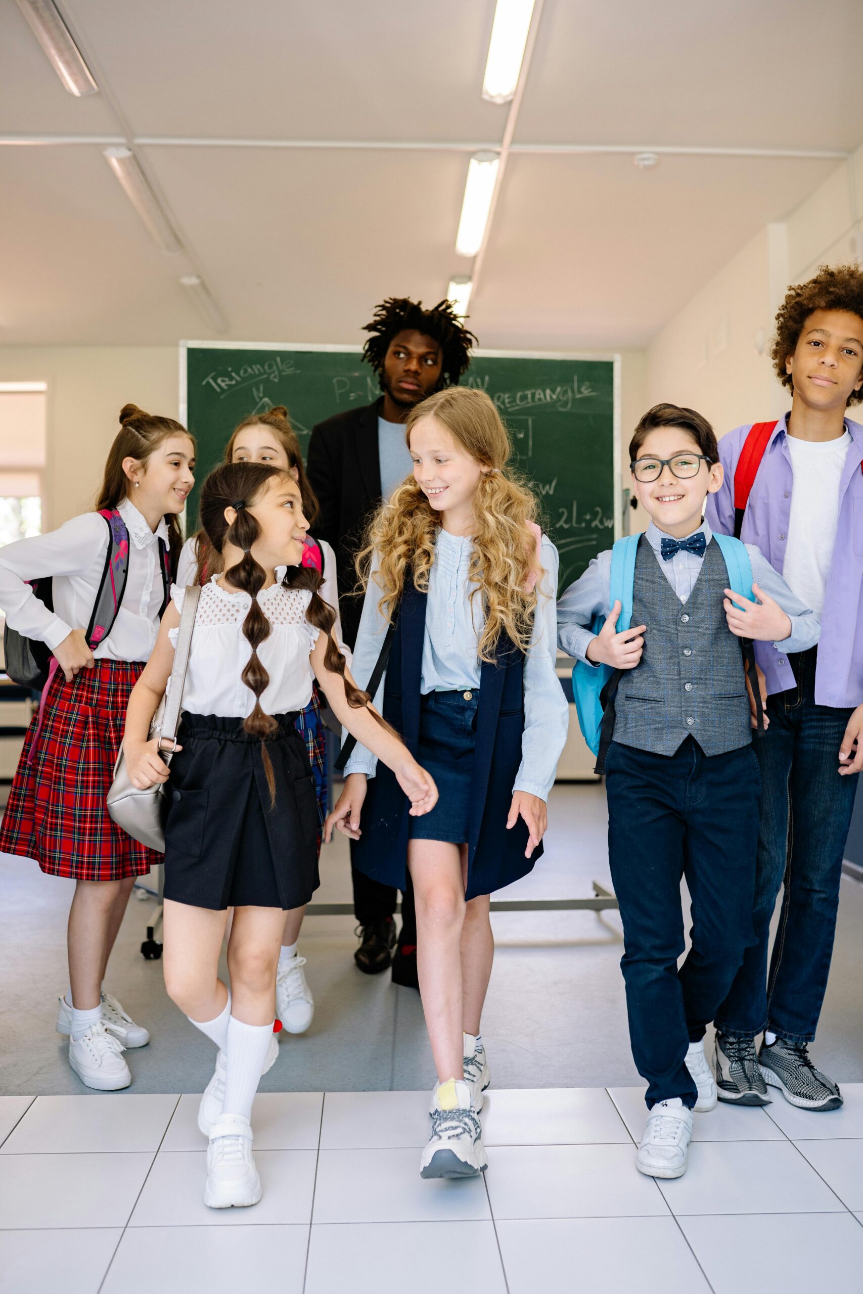 Diverse group of schoolchildren walking in a classroom with a teacher.