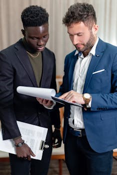 Two business professionals in corporate attire reviewing documents indoors.
