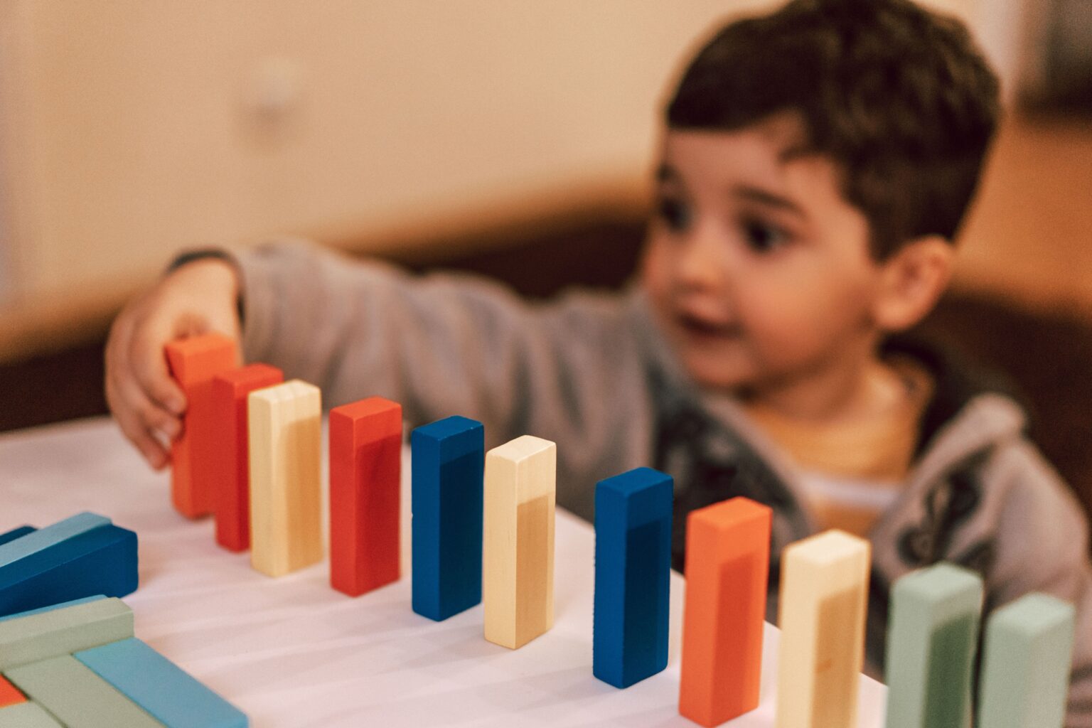 HopeWorks VITAL A young boy plays with colorful wooden blocks indoors, focusing intently and learning through play.