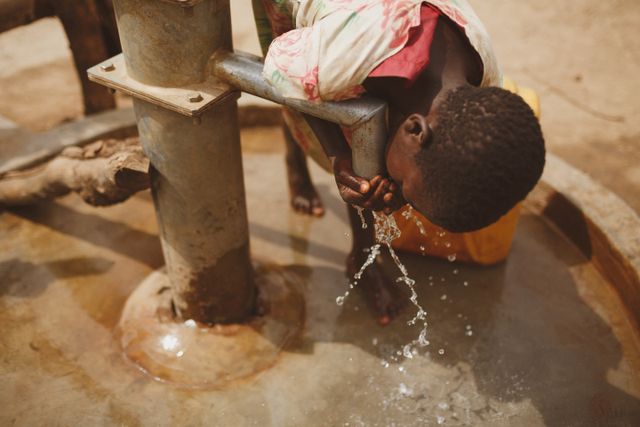 HopeWorks Global Kenya A girl bends to drink clean water from a well in Kitgum, Northern Uganda.