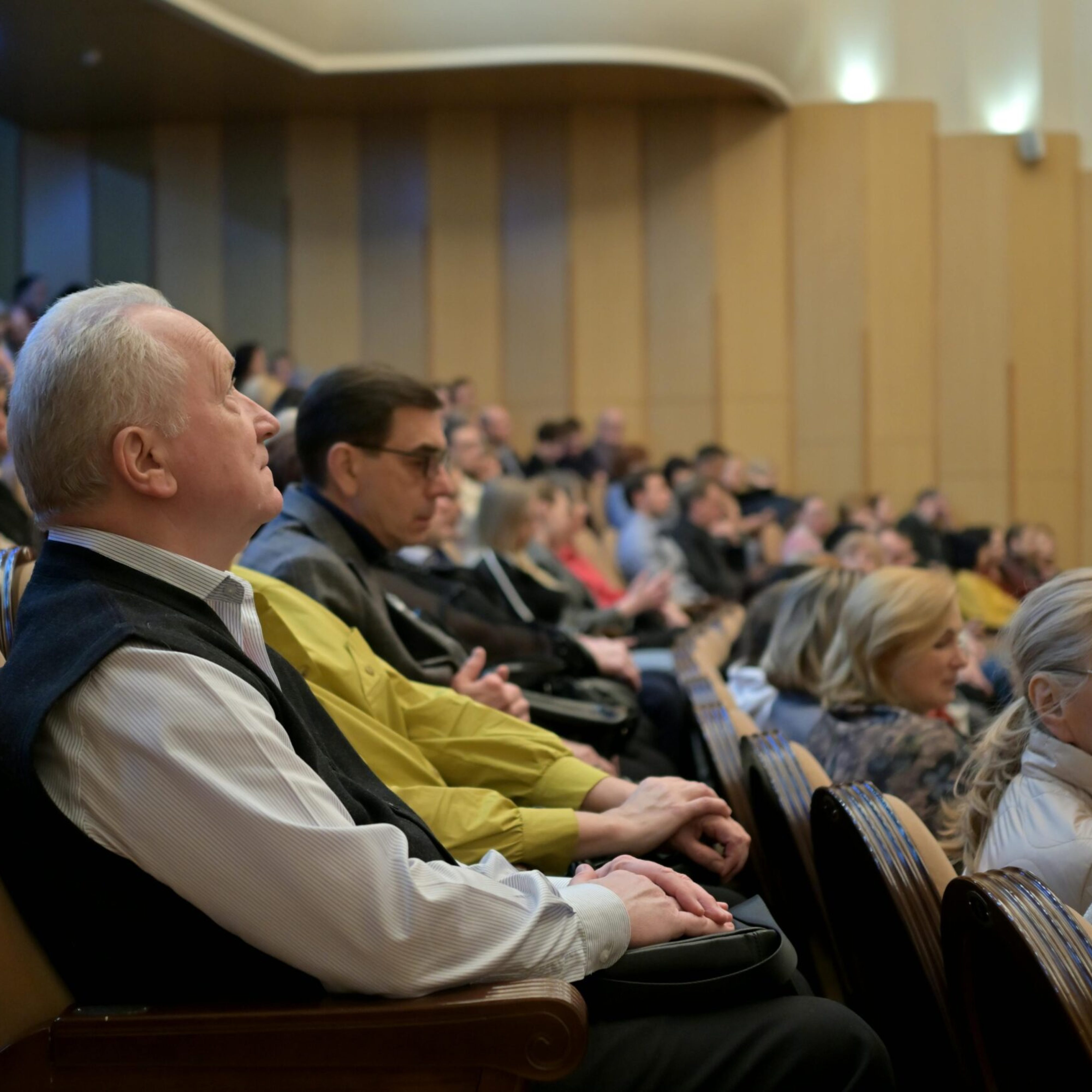 A diverse audience attentively listening during a conference in an auditorium.